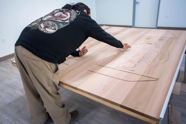 Ahsley Gepcal Joseph recalls the stories he has carved into the doors to the Tzsil Learning Centre photo courtesy Murphy Construction